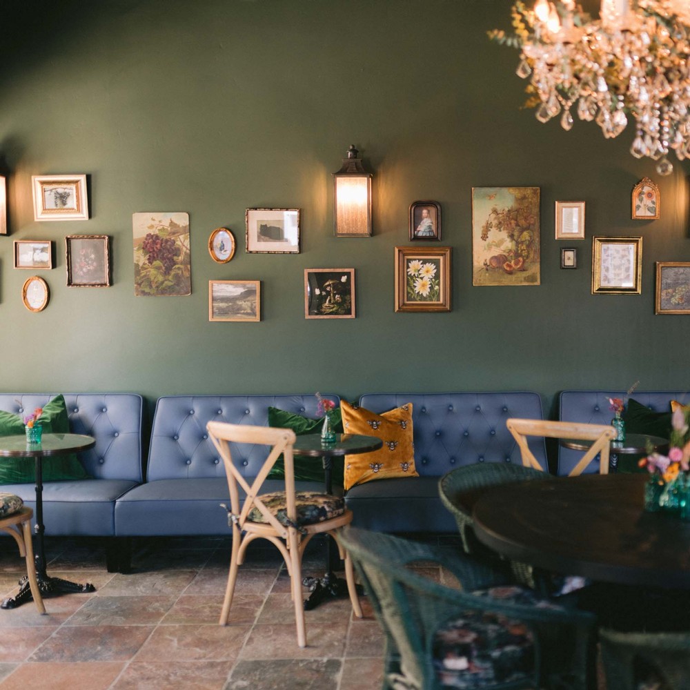 A neon sign that reads "Life is Strange" on the wall above a wooden table at Strange Family Vineyards Tasting Room in Los Olivos, California